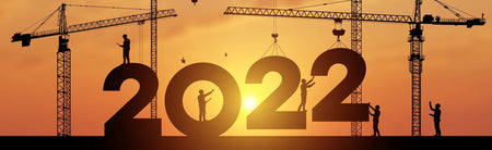 Large construction site silhouette with many construction cranes and workers setting numbers for New Year 2022