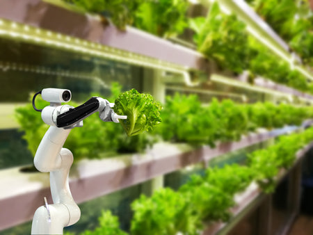 An indoor, vertical farm with stacks of lettuce being harvested by a robotic arm.