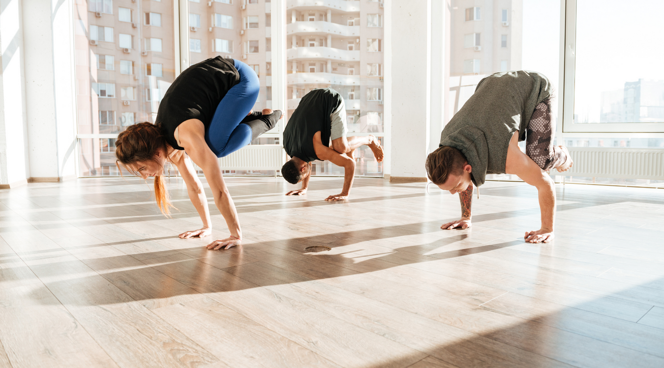 Three people in a yoga class balancing on their hands
