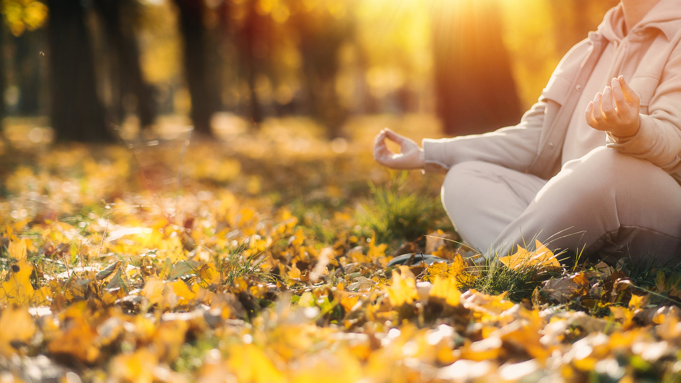 woman in autumn leaves in a park meditating